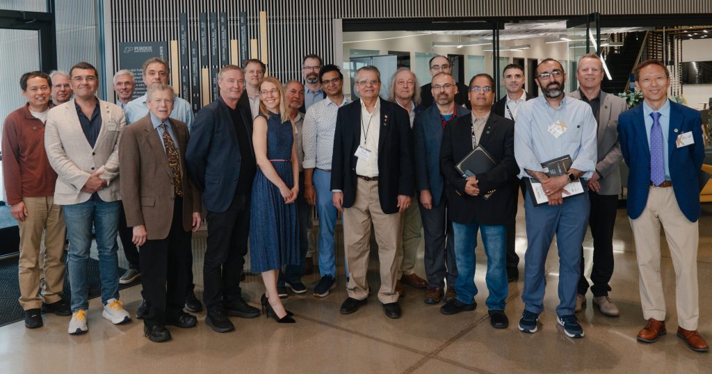 Group of professionals in business attire posing together in a modern office lobby.