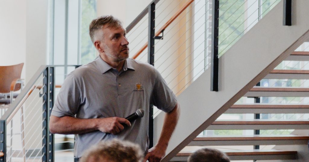 EvoLink CTO Bryan Frazier stands with a microphone in his hand, looking off to the side.