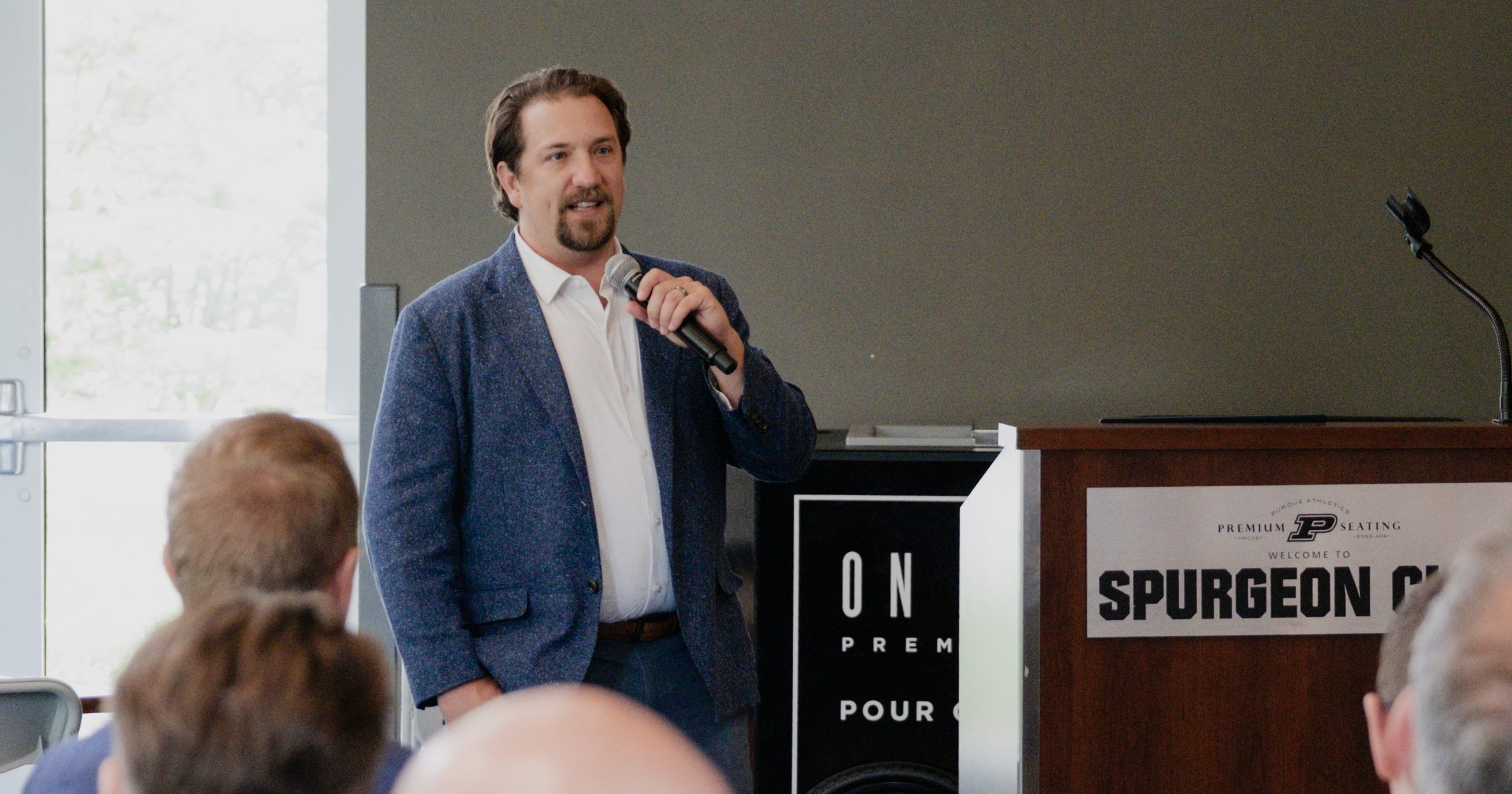 Resolvr Co-Founder Dave Schwab holds a microphone, speaking in front of a crowd.