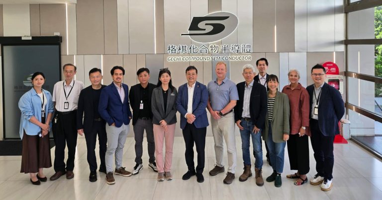 A group of colleagues pose smiling in a bright lobby beneath a company logo and sign reading “GECHI Chemical Semiconductor."